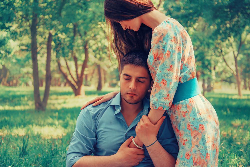 Young loving couple resting in summer park. Woman hugging a man, tender scene. Image with instagram color effect