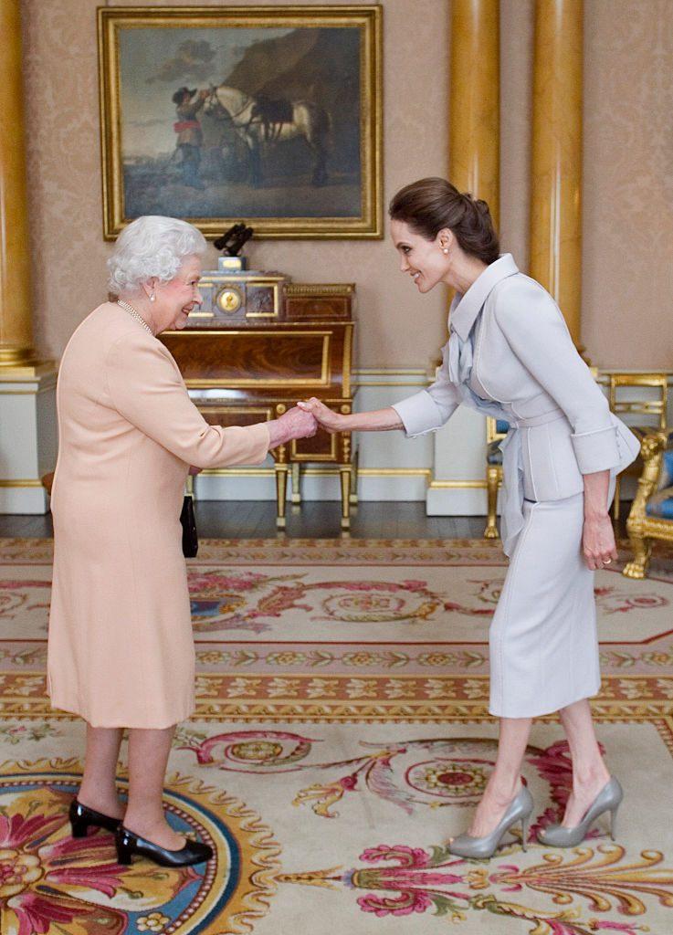 LONDON, ENGLAND - OCTOBER 10: Actress Angelina Jolie is presented with the Insignia of an Honorary Dame Grand Cross of the Most Distinguished Order of St Michael and St George by Queen Elizabeth II in the 1844 Room on October 10, 2014 at Buckingham Palace, London. Jolie is receiving an honorary damehood (DCMG) for services to UK foreign policy and the campaign to end war zone sexual violence. (Photo by Anthony Devlin - WPA Pool/Getty Images)
